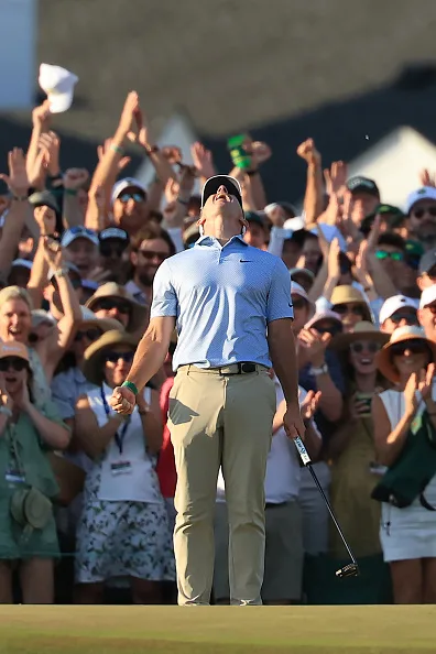 Rory McIlroy looks upward in celebration with a gallery of spectators behind him