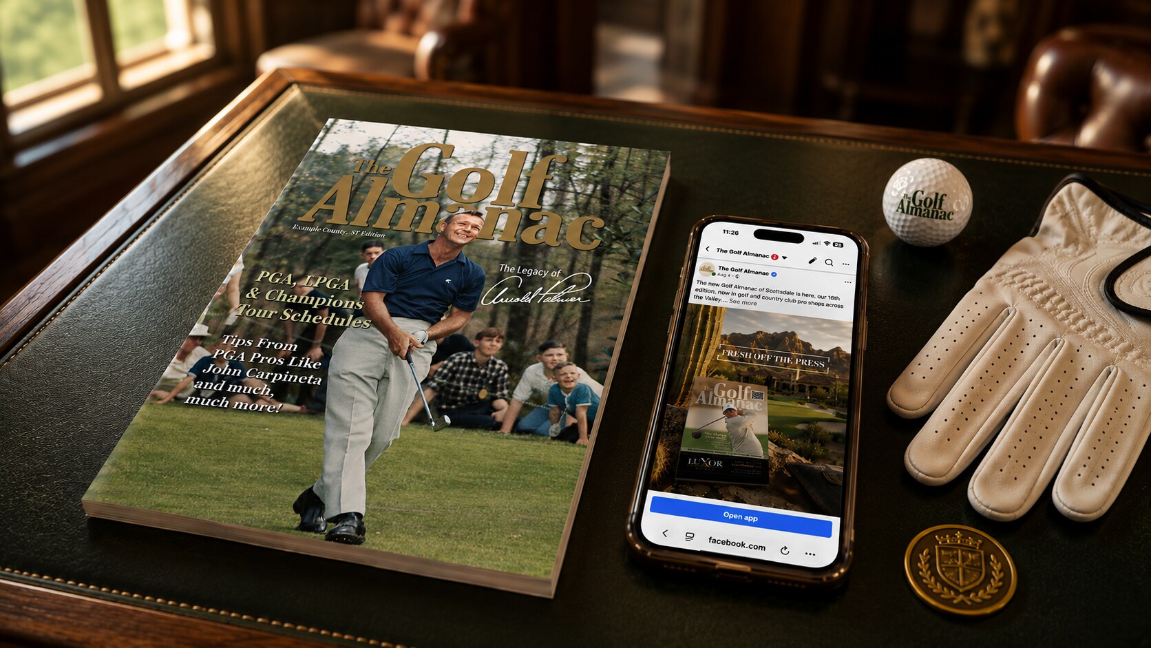 The Golf Almanac magazine and social media page on a phone, arranged with golf accessories on a clubhouse table